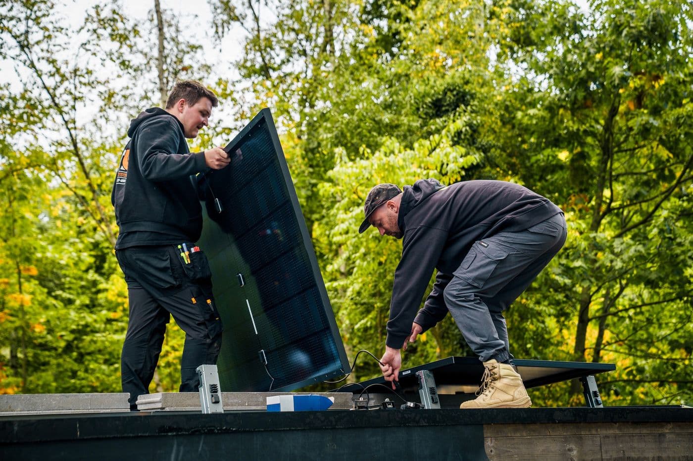 Twee monteurs installeren zonnepanelen op locatie